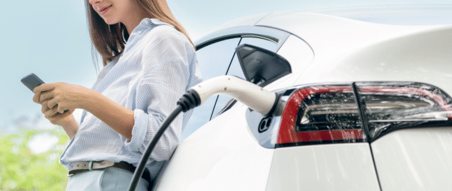 Electric Vehicles Are Shaking Up Auto Financing - Woman Paying bill while charging electronic vehicle